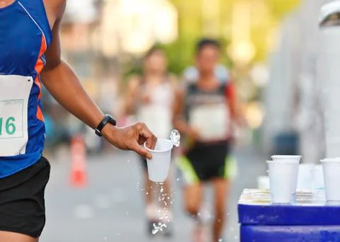 Marathon racer catching cup of water Stock Photos