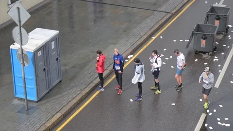 Marathon runners waiting in queue to street public WC cabins in the street Stock Footage 116476064