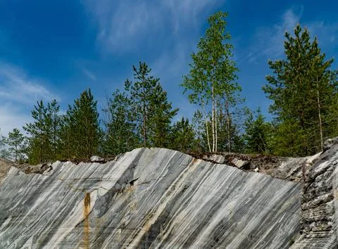 Marble Cliff and Pine Trees under Blue Sky in Karelia Stock Photos