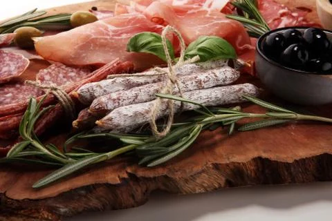 Marble cutting board with prosciutto, bacon, salami and sausages on wooden ba Stock Photos