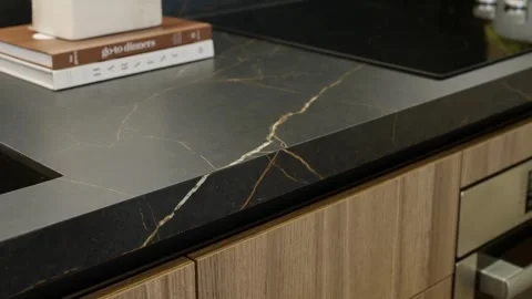 Marble matte kitchen counter with built-in sink, electrical oven and books Stock Footage 249685389