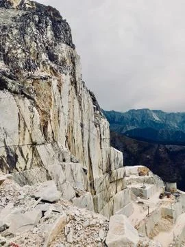 Marble mining, exposed white beige rocky slope of the mountain in Tuscany Stock Photos