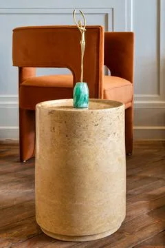 Marble side table with a gold sculpture on top and orange modern chair in t.. Stock Photos