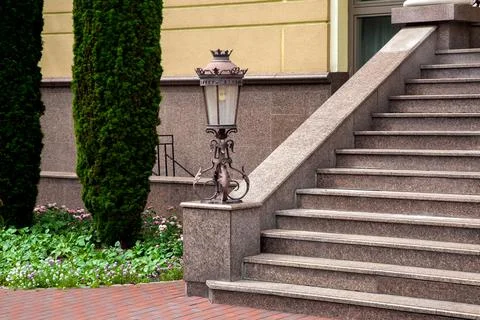 Marble staircase with stone steps and iron forged lantern in retro style. Stock Photos