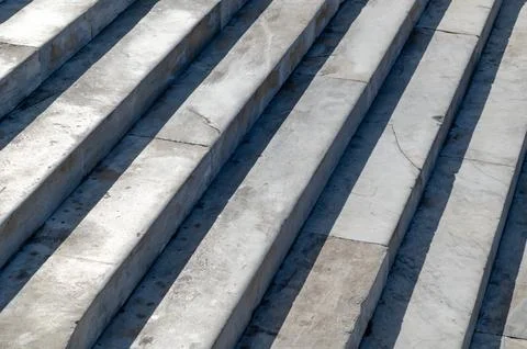 Marble steps descending with diagonal shadows on outdoor staircase Stock Photos