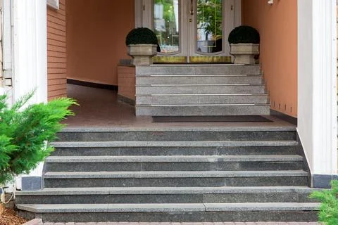 Marble steps rise to threshold of the hotel entrance with stone flowerpot. Stock Photos