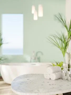 Marble stool table with towels and white ceramic bathtub near green mint wa.. Stock Photos