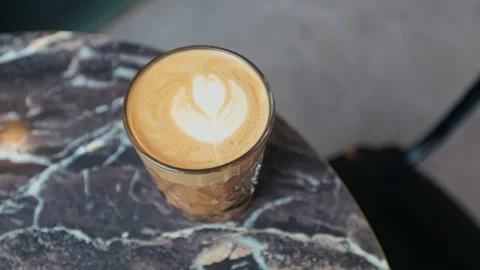Marble table with latte art. Warm natural lighting highlights detailed latte art Stock Footage 330026979