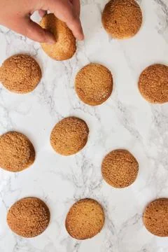 On the marble white table, sandy round cookies, the hand takes the biscuits.. Foto stock