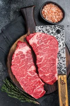 Marbled beef Denver raw meat steak with herbs. Black background. Top view Stock Photos