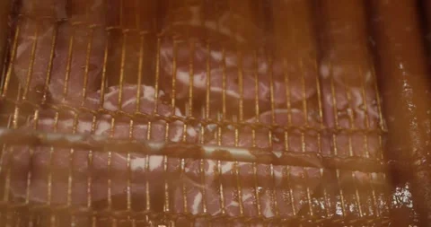 Marbled meat cutlets resting on metal racks inside a steamy smoking chamber at Vídeo Stock 339980005