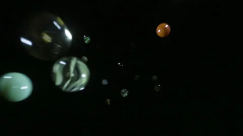 Marbles spheres fall into frame against black background in slow motion Stock Footage 154212414