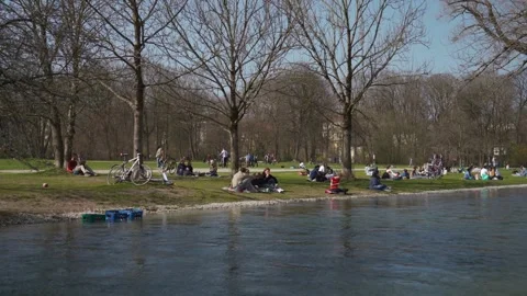 March 22, 2022. Munich, Germany. People relax on green grass near Isar River in Video stock 281609255