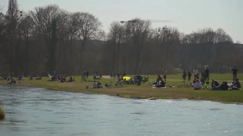 March 22, 2022. Munich, Germany. People relax on green grass near Isar River in Stock Footage 291908695