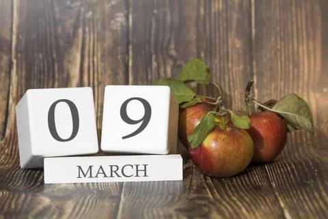 March 9. Day 09 of month. Calendar cube on wooden background with red apples, Фото