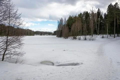 March spring landscape with a small river covered with ice. Stock Photos