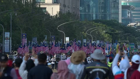 Marching band performing behind a sea of Malaysian flags at the National Day 스톡 동영상 346350014