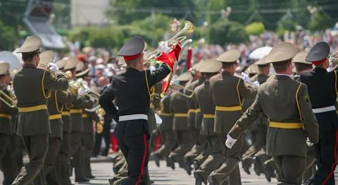 A marching band plays music while moving through a busy square filled with pe Stock Photos