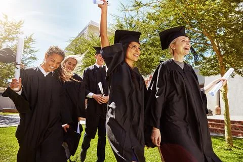 Marching off campus as grads. a group of smiling university students cheering Stock Photos