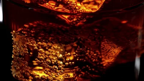 Marco shot of a glass of refreshing soda - Cola on ice cubes Stock Footage
