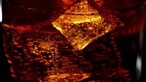 Marco shot of a glass of refreshing soda - Cola on ice cubes Stock Footage