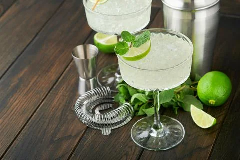 Margarita cocktail with lime, tequila, mint and ice on dark table with amazin Stock Photos