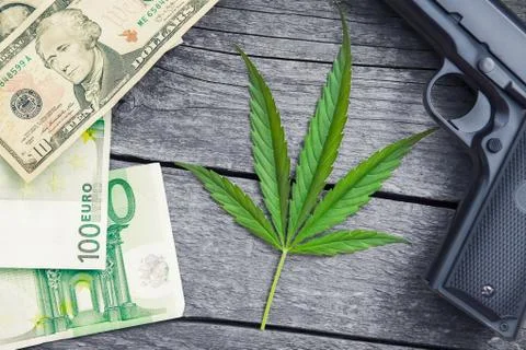 Marihuana leaf.Gun and money around leaf. Stock Photos