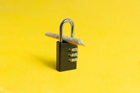 Marijuana cigar between closed padlock. drug sales ban concept Photos