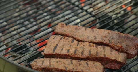 Marinated beef steaks cooking on a charcoal grill 動画素材 336770860