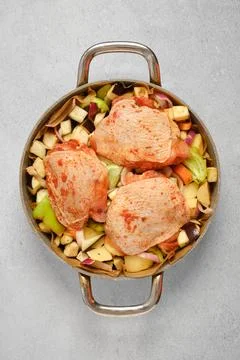 Marinated chicken thighs placed on vegetables before cooking in a pot Foto stock