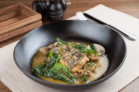 Marinated cod with stewed scallops and spinach, dressed with hazelnut sauce Stock Photos