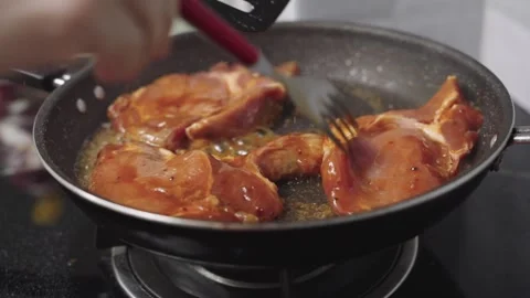 Marinated meat steaks sizzling in a hot frying pan on a kitchen stove. A pe.. Vidéo 340004042