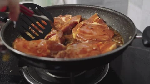 Marinated pork steaks sizzling in a non-stick frying pan on a kitchen stove.. Stock Footage 337623389