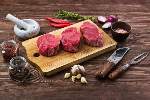 Marinated raw beef steak with spice on wooden table Foto stock
