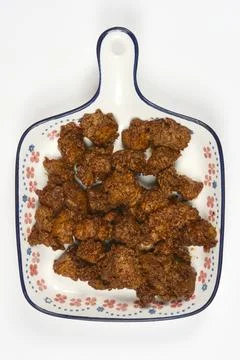Marinated seitan pieces on a patterned ceramic plate Stock Photos