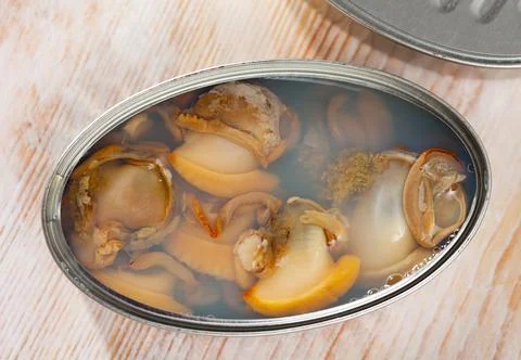 Marinated shellfish in an open tin can on wooden table Stock-Fotos
