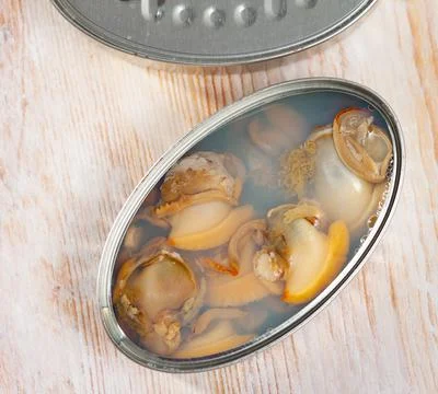 Marinated shellfish in an open tin can on wooden table Stock Photos
