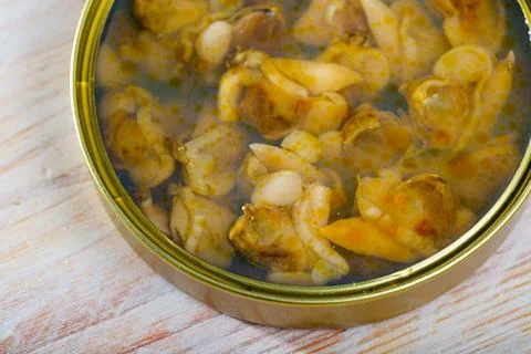 Marinated shellfish in an open tin can on wooden table Stock Photos