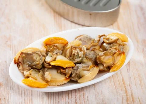 Marinated shellfish in an open tin can on wooden table Stock Photos