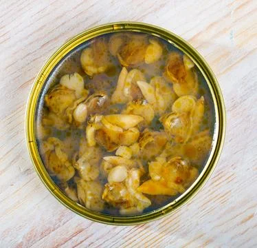 Marinated shellfish in an open tin can on wooden table Stock Photos