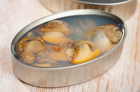 Marinated shellfish in an open tin can on wooden table Stock Photos