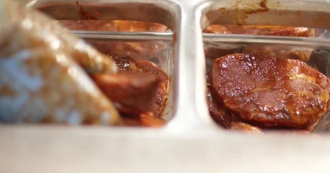 Marinated steaks covered in glossy red spice sauce lying in stainless steel Stock Footage 339982625