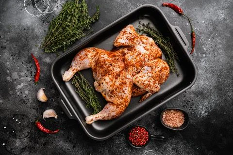 Marinated whole raw chicken tabaka, on black dark stone table background, top Stock Photos
