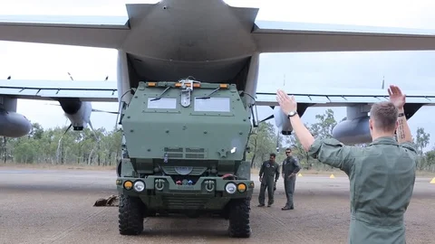 Marine directing M142 HIMARS being driven off C-130 Hercules Stock Footage 112328337