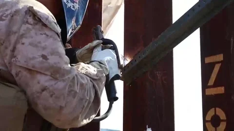 Marine grinding the border security wall as part of security enhancement efforts Stock Footage 300966178
