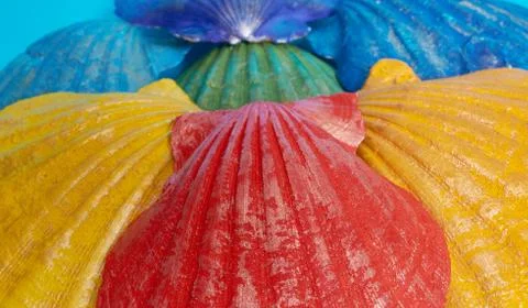 Marine layout. Seven shells painted in rainbow colors on a blue background. Stockfoto's