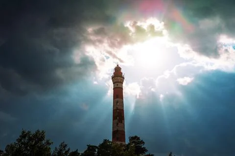 Marine lighthouse against the backdrop of thunderclouds and rays of the sun, Stockfoto's