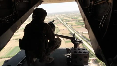 Marine with machine gun looking out of a helicopter onto fields(HD)k Stock Footage 7733641