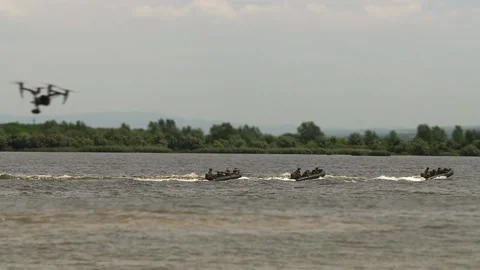 Marines, with weapons in their hands, move on military boats on the river Stock Footage 115583827