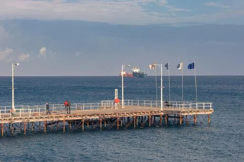 Maritime scene featuring a public dock and commercial vessels Stock Photos
